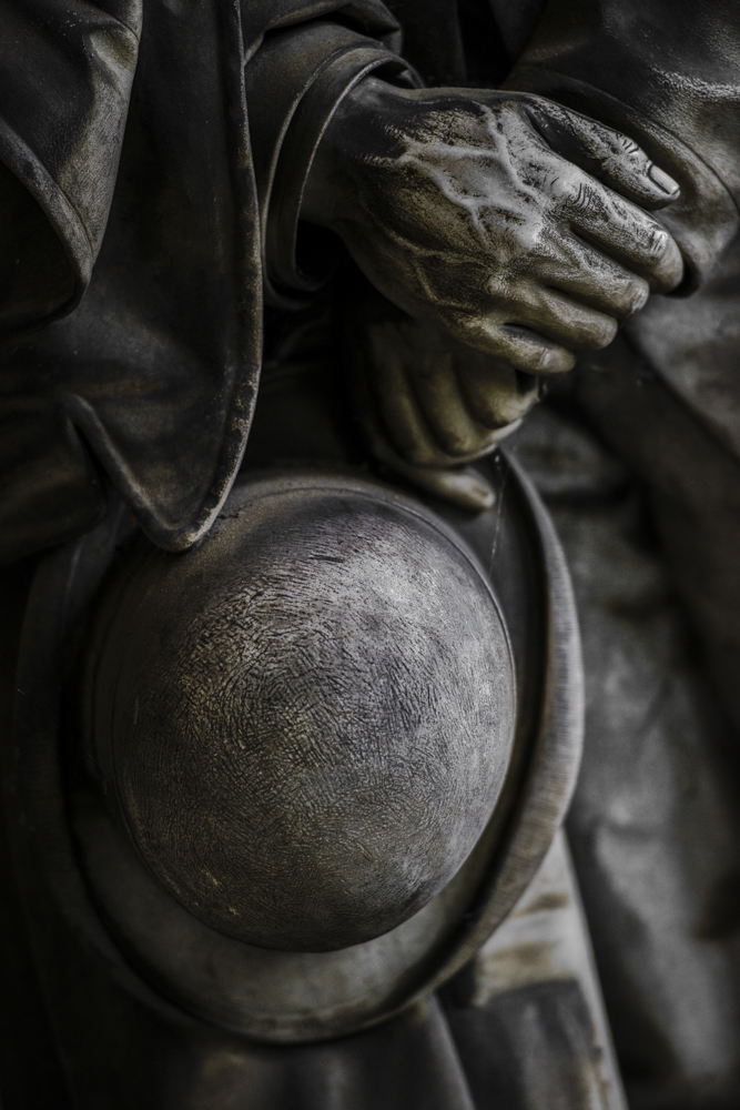 Un silenzio assordante: statua di un uomo che tiene in mano un cappello